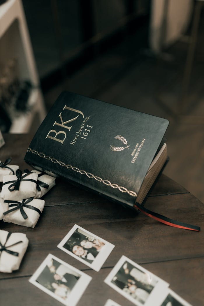 A Bible open on a wooden table with gifts and Polaroid photos, creating a thoughtful and meaningful scene.